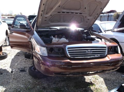 1999 Mercury Grand Marquis - Junkyard scene with a brown Ford Crown Victoria and another vehicle in the background.