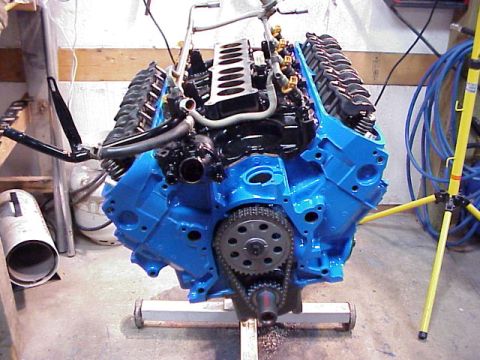 1989 Ford Bronco - A blue V8 engine is mounted on a stand, showing its internal components and timing chain.