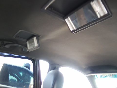 1999 Mercury Grand Marquis - The overhead console of a vehicle shows two illuminated lights and a reflection in the mirror.