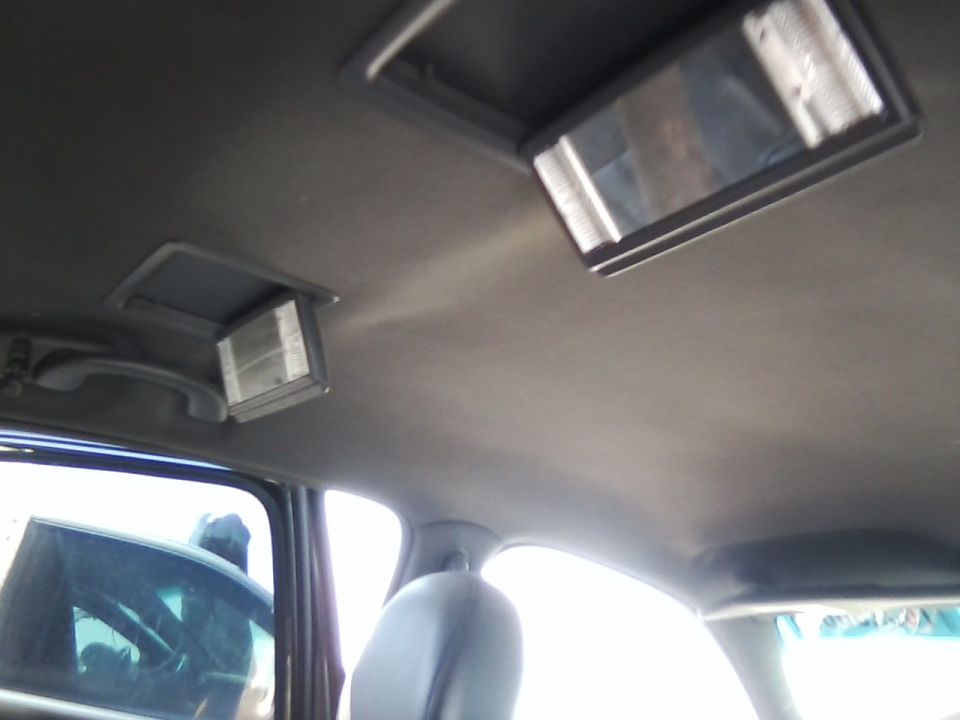 Interior shot of a car's headliner with two overhead lights and a rear-view mirror visible