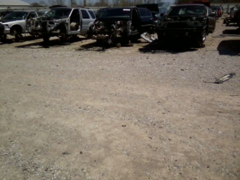 1999 Mercury Grand Marquis - Multiple vehicles are seen in various states of disrepair at a junkyard.