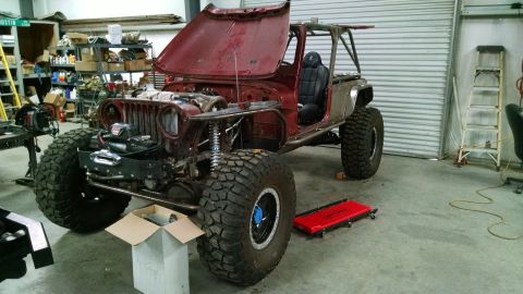 Modified Jeep CJ in a garage with hood open and roll cage installed