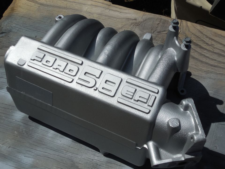 Silver Ford 5.8 EFI intake manifold on weathered wood