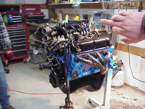 1989 Ford Bronco - Engine on a stand in a workshop setting, with tools and equipment visible.