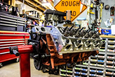 1979 Ford Bronco - A V8 engine is mounted on a stand in a workshop, surrounded by tools and storage cabinets.