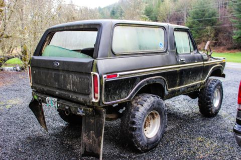 1979 Ford Bronco - Rear view of a lifted black 1979 Ford Bronco, modified with large off-road tires and mud flaps.