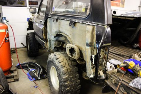 1979 Ford Bronco - The rear quarter panel of a black SUV is removed, revealing the interior structure and showing the vehicle in a state of repair.