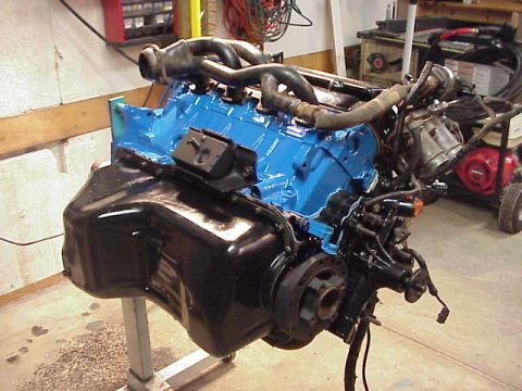 1989 Ford Bronco - Engine assembly on a stand in a workshop, with various hoses and wiring attached.