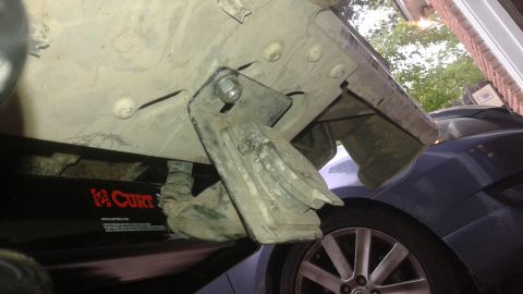 1996 Ford Bronco - The underside of a vehicle is shown, with a trailer hitch assembly and a blue car visible in the background.