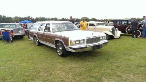 2000 Mercury Grand Marquis - Station wagon with wood paneling is parked on a grassy field at an outdoor car show.