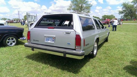 2000 Mercury Grand Marquis - A silver station wagon is parked on a grassy field with other vehicles and people in the background.