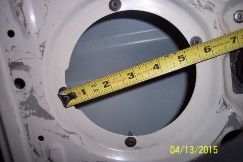 1990 Ford Bronco - A tape measure is used to check the size of a speaker mounting hole in a vehicle's door panel.