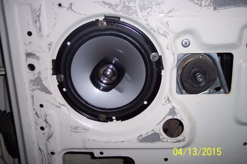 1990 Ford Bronco - Close-up view of a door speaker and the internal window regulator mechanism within a vehicle's door panel.