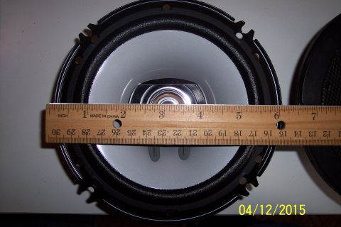 1990 Ford Bronco - A car speaker is measured with a wooden ruler, showing its size.
