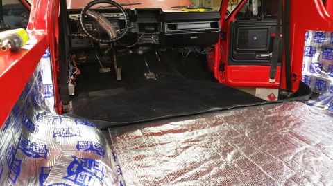 1983 Ford Bronco - Interior view of a red truck undergoing sound deadening and carpet installation.