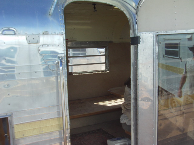 Interior view of an aluminum trailer showing a window, bench, and doorway