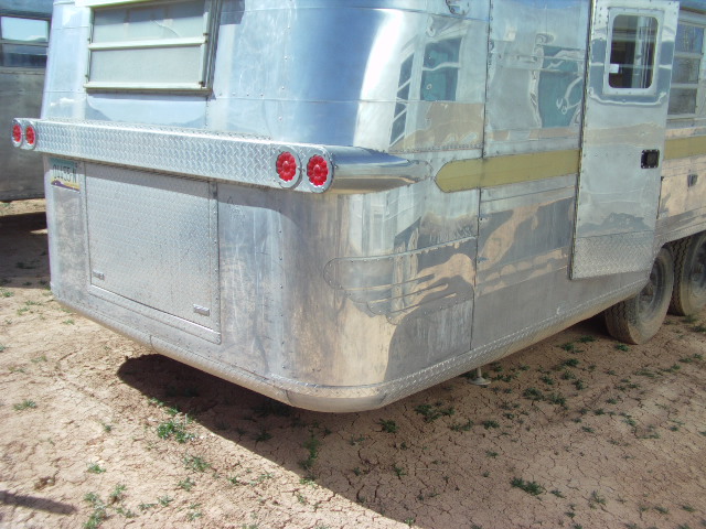 rear of shiny aluminum trailer with dual red taillights and diamond plate bumper