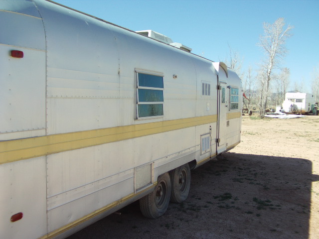 Side view of a silver and yellow travel trailer with dual axles