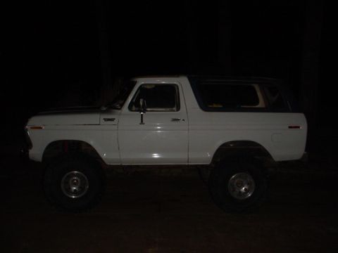 1979 Ford Bronco - A white Ford Bronco is parked outdoors at night, its side profile illuminated against the dark background.