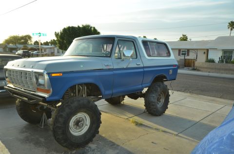 1979 Ford Bronco - Modified 1978 Ford Bronco with significant lift and oversized tires sits on a residential street.