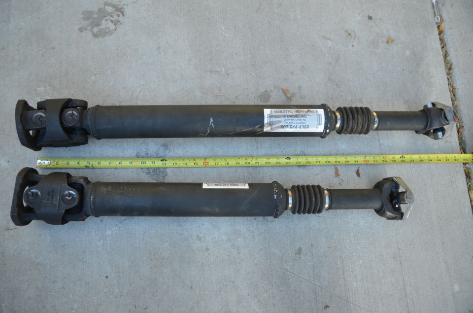 two drive shafts laid out with a tape measure