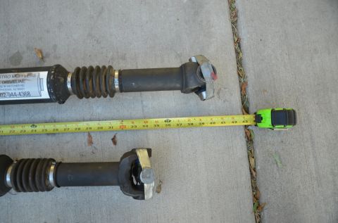 1979 Ford Bronco - Two drive shafts are laid out on a concrete surface with a tape measure indicating their length.