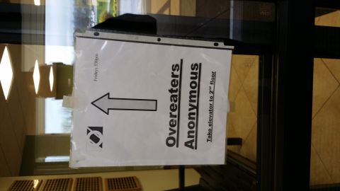 2007 Subaru Impreza - Sign indicates Overeaters Anonymous meetings are held Fridays at 5:30pm and advises to take the elevator to the 2nd floor.