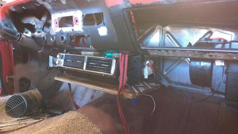 1964 Ford Fairlane - The dashboard of a vehicle is partially disassembled, revealing the interior structure and an installed AC unit.