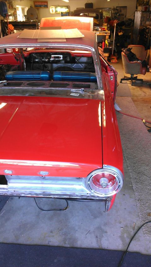 1964 Ford Fairlane - The interior of a red 1964 Ford Fairlane shows blue seats and unfinished body panels, indicating ongoing restoration work.