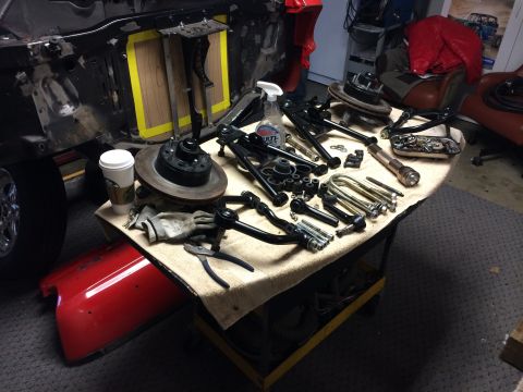 1964 Ford Fairlane - Various automotive suspension components are organized on a table, ready for installation on a vehicle undergoing repairs.