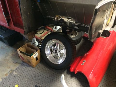 1964 Ford Fairlane - A red car fender and frame are visible, with a chrome wheel and tire mounted.
