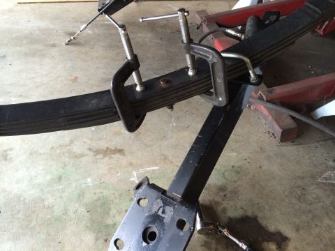 1964 Ford Fairlane - A vehicle's leaf spring is secured with C-clamps during a repair or modification.