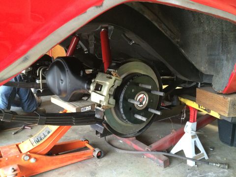 1964 Ford Fairlane - Car's rear suspension and braking system are being worked on, supported by a jack and stands.