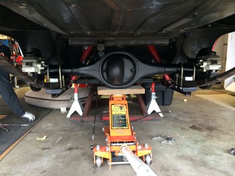 1964 Ford Fairlane - Underside view of a vehicle's rear axle assembly, disc brakes and leaf springs, undergoing maintenance.