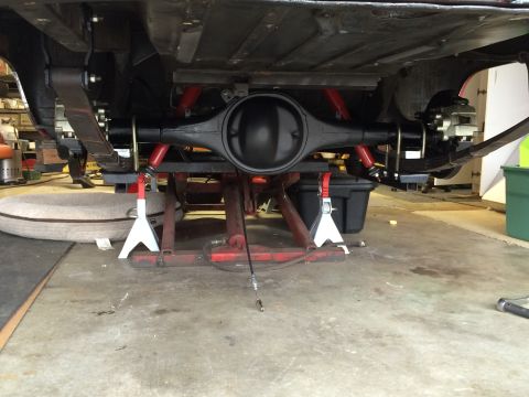 1964 Ford Fairlane - Underside view of a vehicle's rear axle assembly being worked on in a garage.