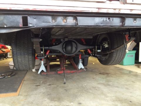1964 Ford Fairlane - Underside view of a vehicle's rear axle and suspension system, undergoing maintenance or repair.