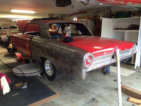 1964 Ford Fairlane - A 1964 Ford Fairlane is in a garage, showing its rear end with a mix of red paint and bare metal panels.