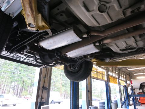 1991 Ford LTD Crown Victoria - Undercarriage of a car on a lift, showing the exhaust system and rear axle.
