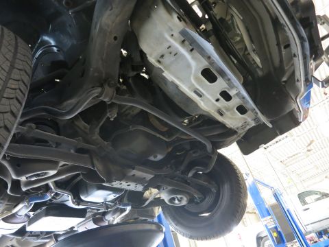 1991 Ford LTD Crown Victoria - The underside of a 1991 Ford Crown Victoria LTD is visible, lifted on a mechanic's hoist.