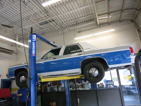 1991 Ford LTD Crown Victoria - A 1991 Ford Crown Victoria LTD is raised on a car lift inside a service bay.
