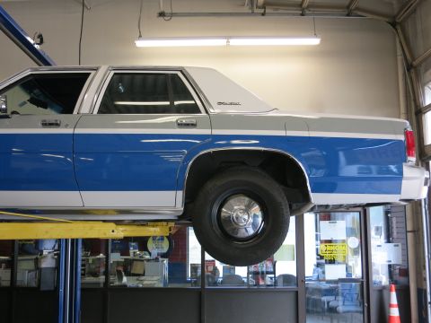 1991 Ford LTD Crown Victoria - This sedan, likely from the 1980s, is elevated on a lift in a garage.