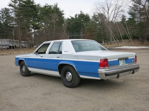 1991 Ford LTD Crown Victoria - This sedan displays a two-tone paint scheme with blue and gray sections separated by a white stripe.