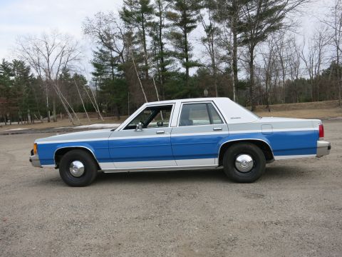 1991 Ford LTD Crown Victoria - This sedan features a distinctive two-tone paint scheme with a blue stripe separating the gray upper and lower body panels.