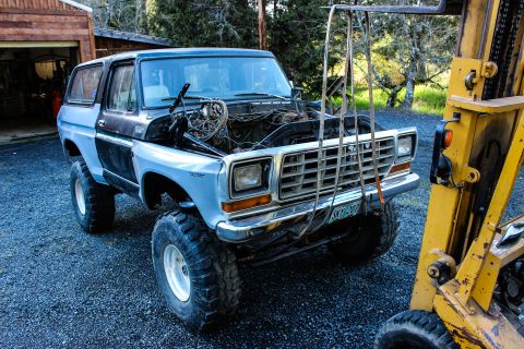 1979 Ford Bronco - Late-1970s Ford Bronco, gray and black two-tone, lifted on large tires with the hood removed during a build.