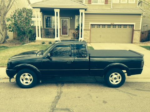 2001 Ford Ranger - Side view of a black 2001 Ford Ranger pickup truck parked in front of a suburban house.