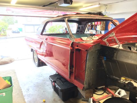 1964 Ford Fairlane - A red coupe is in a garage, stripped down and undergoing restoration work.