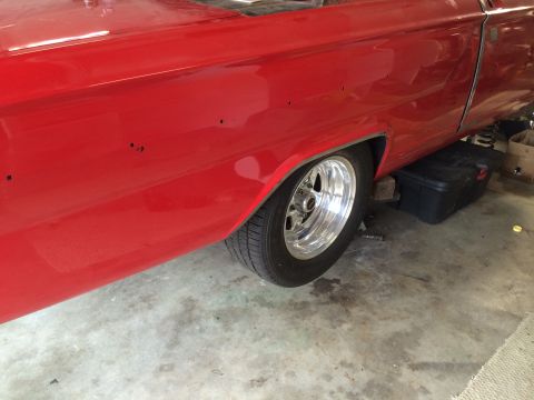 1964 Ford Fairlane - The rear side of a red 1964 Ford Fairlane is shown, with a shiny chrome wheel and tire.
