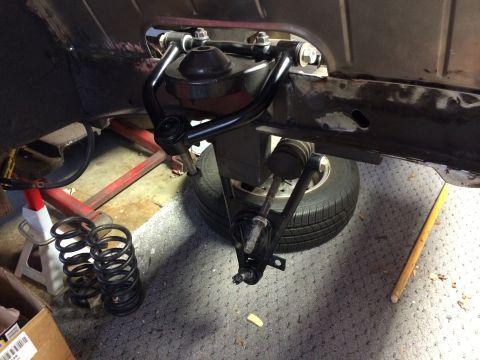 1964 Ford Fairlane - Close-up of a car's front suspension system, showing control arms and springs during a repair.