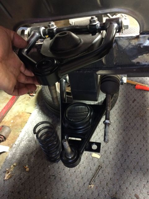 1964 Ford Fairlane - A close-up view of a car's suspension system, showing a control arm, coil spring, and ball joint.