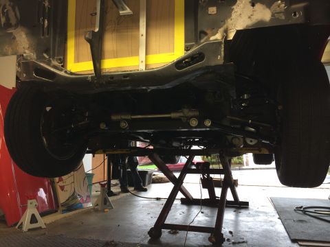 1964 Ford Fairlane - The underside of a vehicle is shown, suspended on a lift for maintenance or repair work.